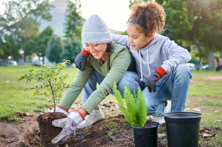 Lady and a girl planting little trees in pots